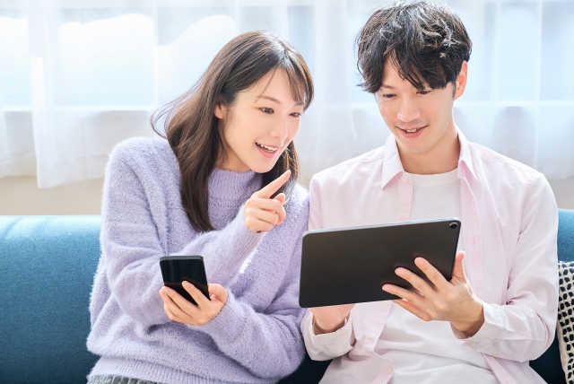 スマホとタブレットの画面を見比べている男女